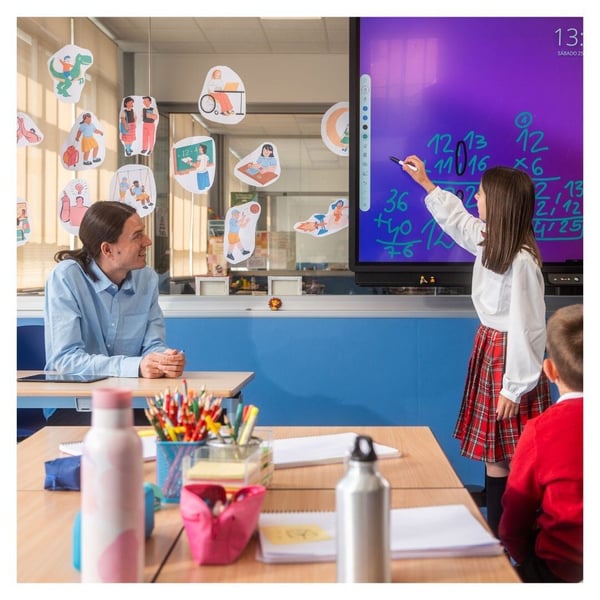 A student writes an equation on a smart board