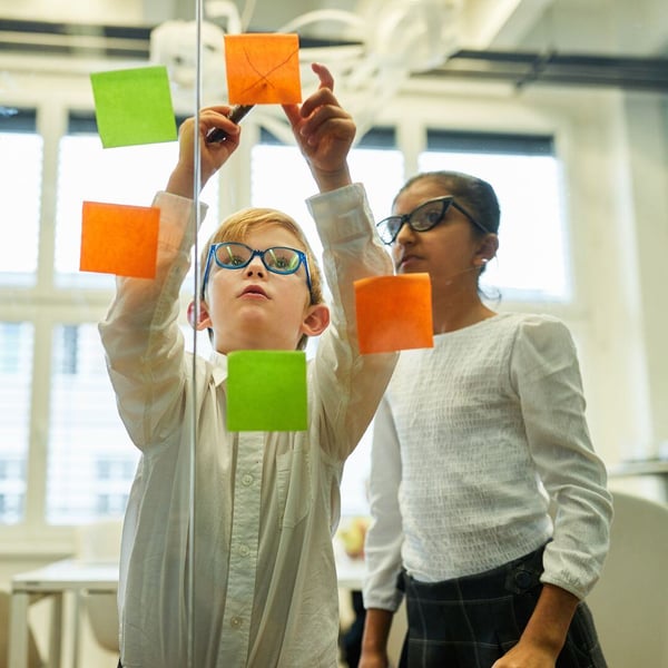 children working with sticky notes on a board