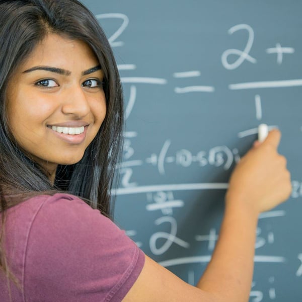 Student completing math problem on chalkboard