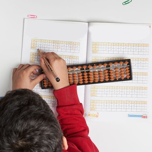 a child filling out a math chart with an abacus