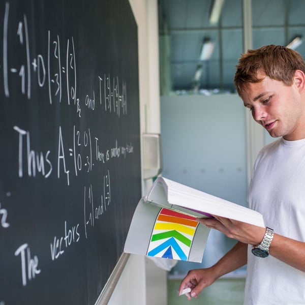 Student completing math problem on chalkboard